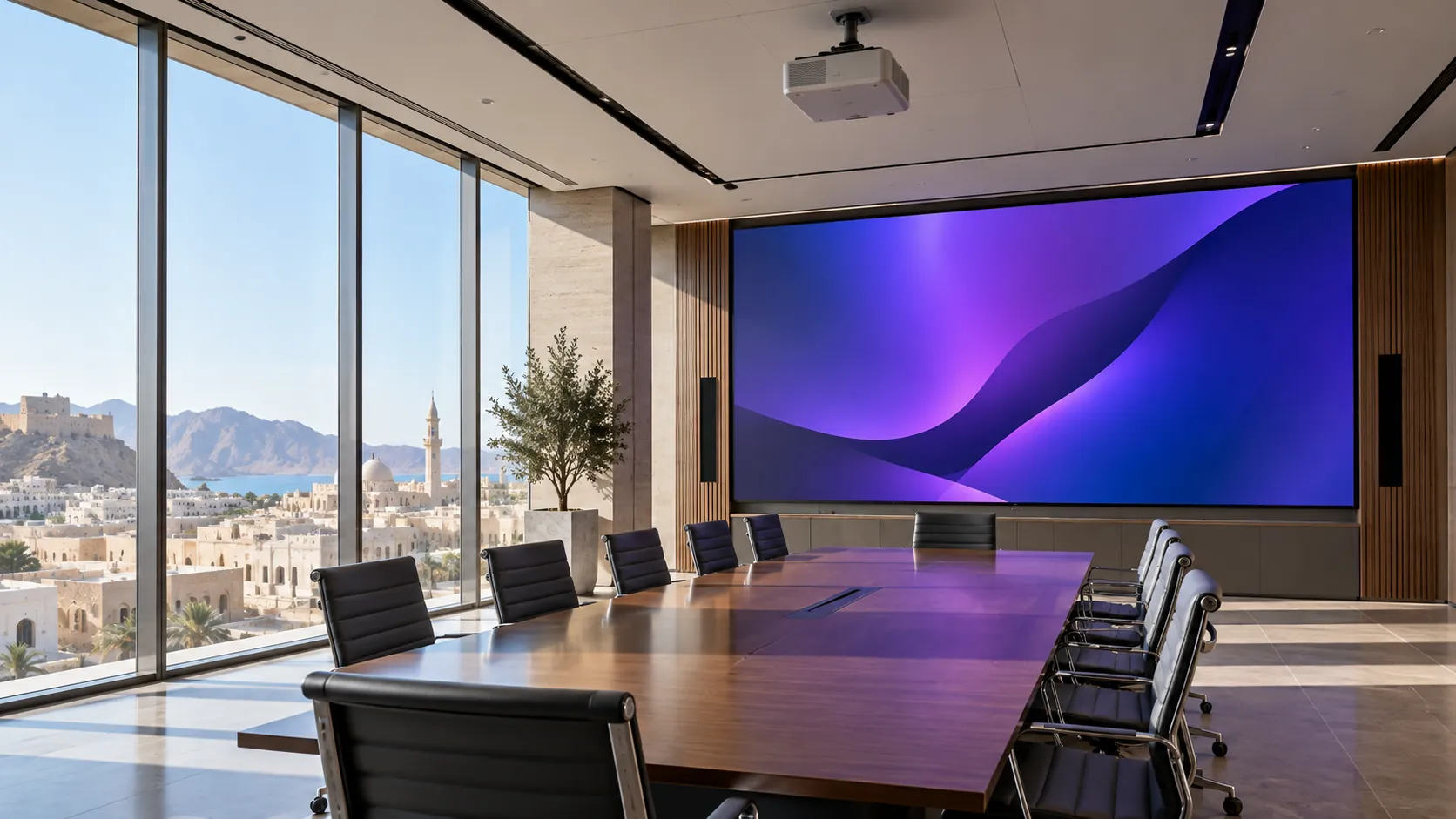 Glass-walled boardroom overlooking Muscat with a large LED video wall at the end of the table and a ceiling-mounted projector